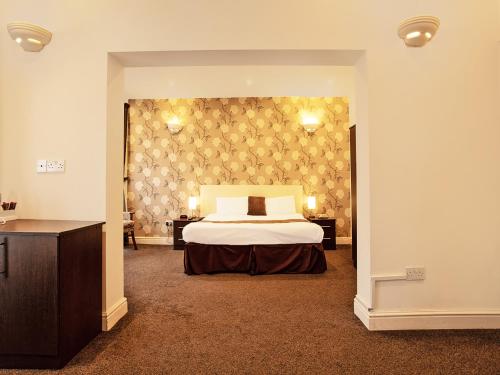 大雅茅斯The Waverley Hotel的一间卧室设有床和两张桌子,还有一面墙