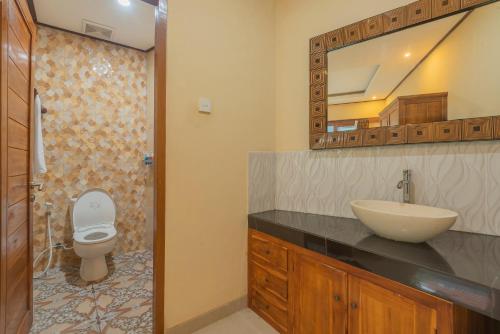 勒吉安Liliy Guest House Kuta - Badung的一间带水槽、卫生间和镜子的浴室