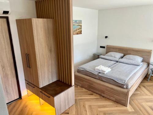 奈达Apartamentai KOPOS Nidoje的一间卧室配有一张床和一个木制橱柜