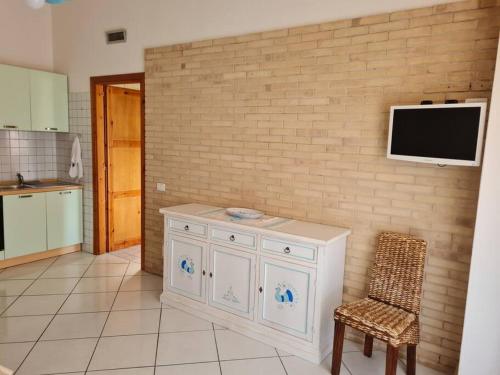 维拉西米乌斯Casa Alessandro的厨房配有白色橱柜,砖墙上配有电视