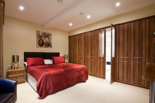 滨海凯斯特Premier Apartments的一间卧室配有一张红色的床和木制橱柜。