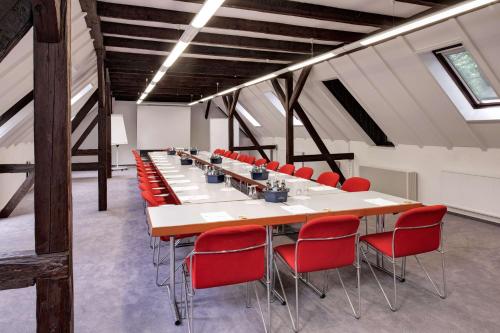 德累斯顿艾克城堡酒店的一间会议室,配有长桌子和红色椅子