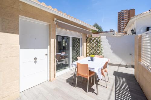 贝尼多姆Apartamento ALMA con terreno privado y parking compartido - a 800m de Playa Poniente的阳台的庭院配有白色的桌椅