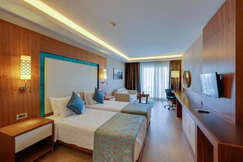 库萨达斯Ramada Hotel & Suites by Wyndham Kusadasi的酒店客房,设有两张床和一张沙发