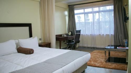 KisiiUfanisi Resort - Kisii的一间卧室配有一张床、一张书桌和一个窗户。