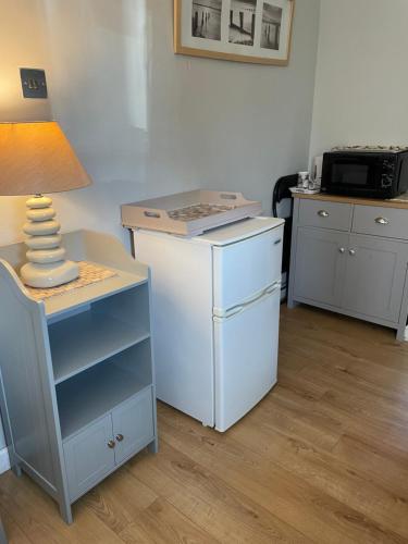 WarsashCove Cott的客房设有带台灯的桌子和冰箱。