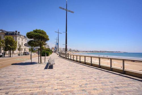 莱萨布勒-多洛讷La Maison des sables , 300m de la plage的海滩旁人行道上的长凳