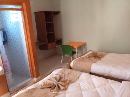KaratinaMWAHE RESORT的一间卧室配有两张床、一张桌子和一把椅子