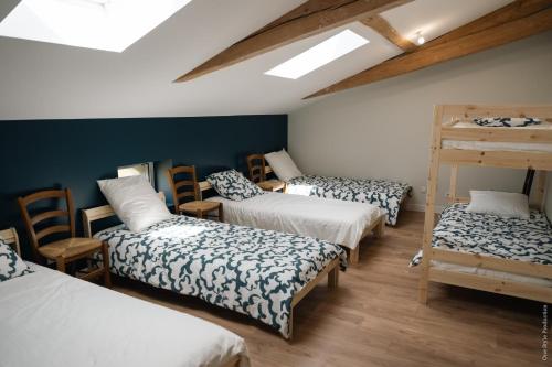HostensEntre Chênes et Pins - Gîte de groupe 3 étoiles的客房设有四张床、木椅和天窗。