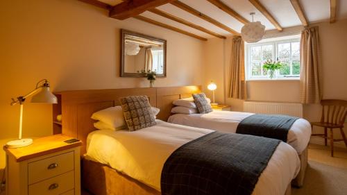 奇平卡姆登Old Mill Barn的一间卧室设有两张床和窗户。