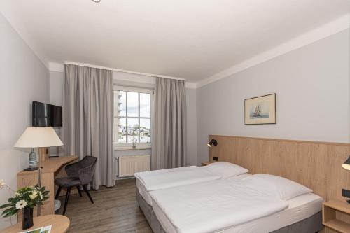 萨斯尼茨萨斯尼茨库恩酒店的配有一张床、一张书桌和一扇窗户的酒店客房