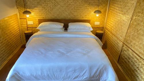 大吉岭Deoja Forest Stay的一间卧室配有两张带白色床单和两张灯的卧室