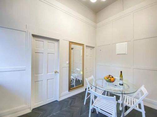 萨法德Mendis accommodation的一间设有玻璃桌和白色椅子的用餐室