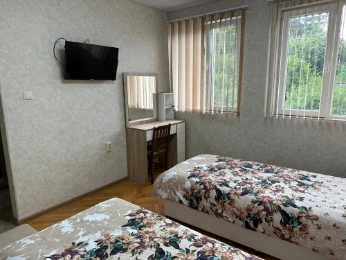 BelimelSuhin Dol Hotel的一间卧室设有两张床,墙上配有电视。