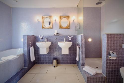 乌赫斯特海斯特Villa Beukenhof的浴室设有2个水槽、2面镜子和1个浴缸