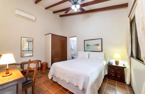 卡利斯坦殖民地酒店的卧室配有白色的床、桌子和书桌