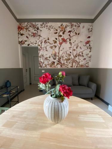 比萨Blom apartments的花瓶,花朵红色,坐在桌子上