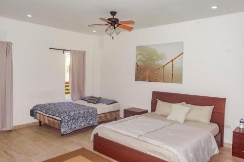 Dixon CoveLas Palmas Beach Hotel的一间卧室配有两张床、风扇和椅子