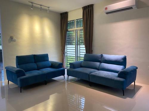 而连突GEYI HOMESTAY的客厅配有2张蓝色的沙发和窗户