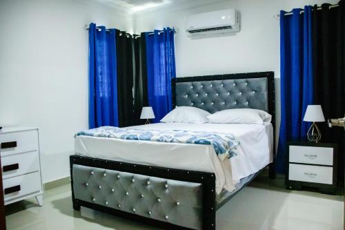 圣地亚哥洛斯卡巴3 BR apartment ciudad santiago de los caballeros的一间卧室配有一张带蓝色窗帘的大床