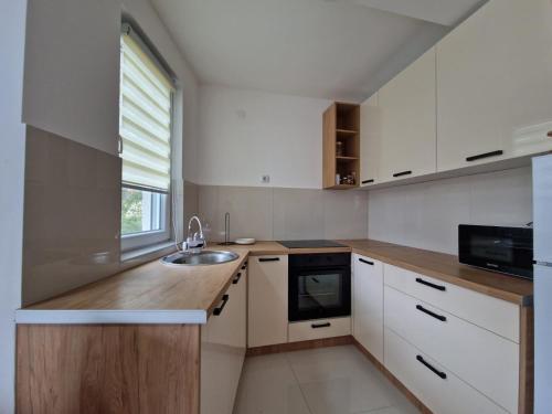 皮罗特N&M Apartment的厨房配有白色橱柜、水槽和窗户。