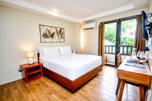 长滩岛Serene La Playa Boracay的一间卧室配有一张床、一张书桌和一个窗户。