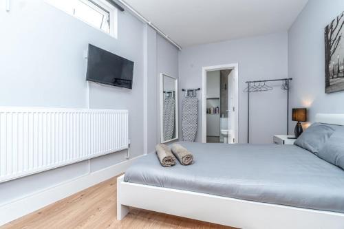 伦敦Modern Apartment in East London的一间白色卧室,配有床和电视