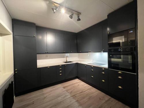 贝勒沃格Storgata 5的厨房配有黑色橱柜和白色台面