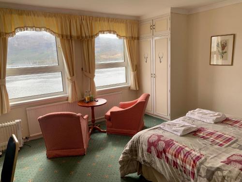 洛哈尔什教区凯尔高地Lochalsh Hotel with Views to the beautiful Isle of Skye的一间卧室配有两把椅子、一张床和两个窗户。