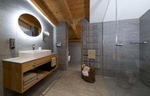 萨姆瑙恩Aparthotel Grischuna的浴室配有盥洗盆和带镜子的淋浴