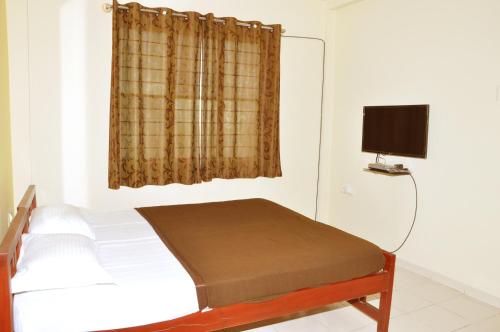 班加罗尔维加居住宾馆的一间卧室设有一张床和一个带电视的窗户。