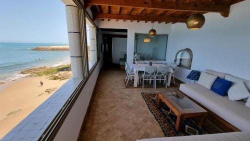艾西拉Chambre bord de mer的海滩上的阳台配有沙发和桌子