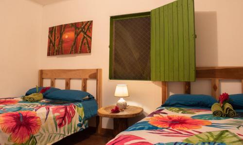 利蒙港Finca D'Elía Lodge的客房设有两张床和一张带台灯的桌子。