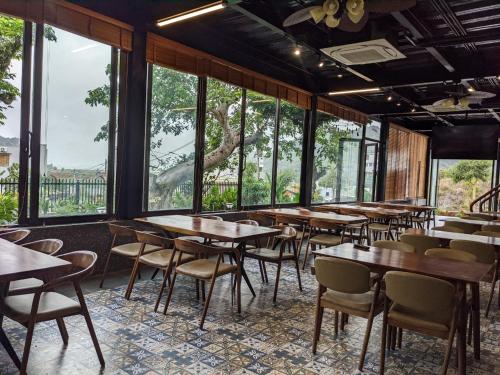 吉婆岛Eden Hotel Cát Bà的餐厅设有桌椅和大窗户。
