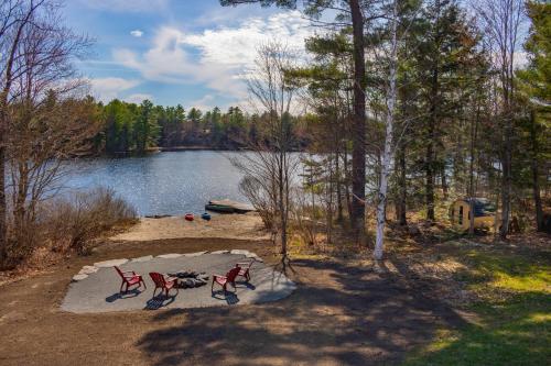 帕里桑德Perfect 3 bedroom waterfront muskoka cottage的两把红色椅子坐在湖边