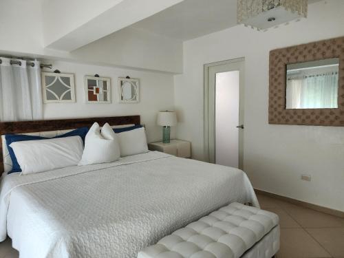 璜多里奥3 bedroom, front of the beach and pool的卧室配有一张白色大床和长凳