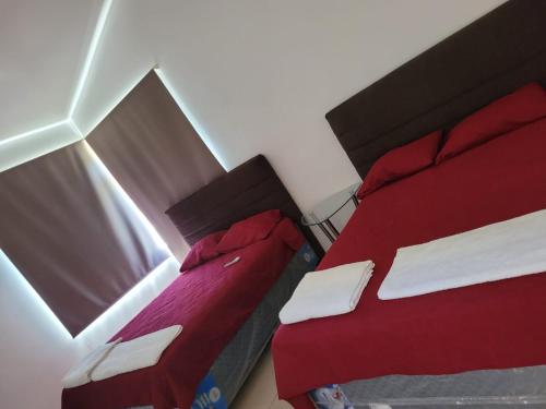 IztapaCasa en condominio monterrico的小客房内的两张床,配有红色床单