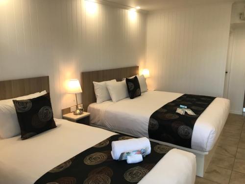 金格罗伊Room Motel Kingaroy East的酒店客房设有两张床和两盏灯。