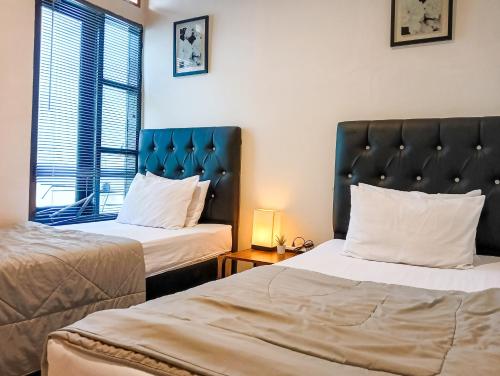 井里汶Sleep House 2BR Wifi Unlimited的酒店客房设有两张床和窗户。