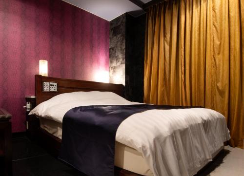 TatsunoHOTEL ZERO的卧室配有一张床铺,位于一间粉红色墙壁的房间