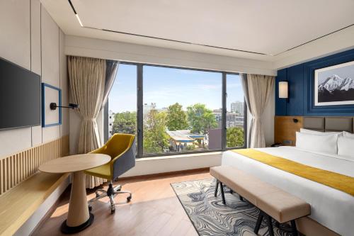 西里古里Ramada Encore by Wyndham Siliguri Sevoke Road的酒店客房设有一张床和一个大窗户