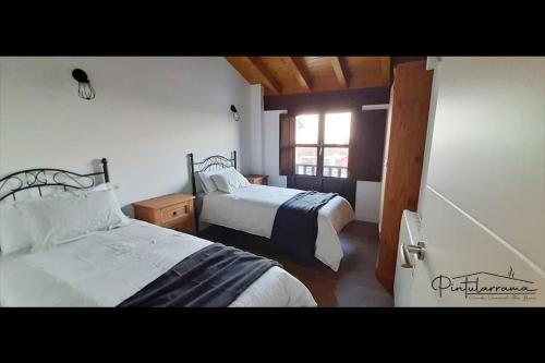 博迪利奈斯Pintularrama - Casa Rural en Póo de Llanes的一间卧室设有两张床和窗户。