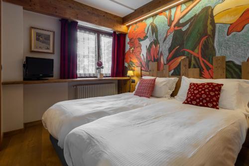 布勒伊-切尔维尼亚Hotel & Ristorante Serenella的卧室配有一张大床,墙上挂有绘画作品
