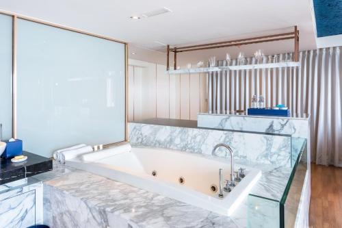 芭堤雅市中心芭堤雅A1皇家游轮酒店 - SHA Extra Plus的一间带玻璃墙浴缸的浴室