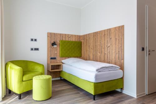 于特博格Hotel Fuchsbau Jüterbog的一间卧室配有一张床和一把绿色椅子