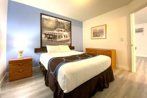 希卡姆斯西卡穆斯速8汽车旅馆的卧室配有一张大床,墙上挂有绘画作品