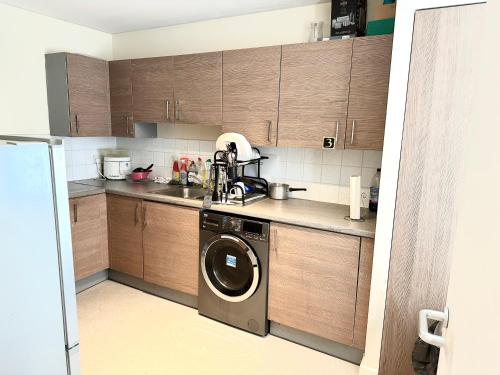 伦敦Comfortable Private Room in Bermondsey的厨房配有木制橱柜和洗衣机。