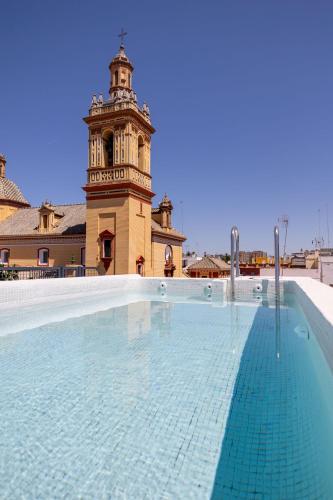 塞维利亚New! Ohliving San Bernardo的一座带钟楼建筑前的游泳池