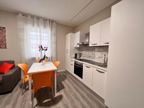 圣乔瓦尼·罗通多Helios的厨房配有白色橱柜和一张带橙色椅子的桌子