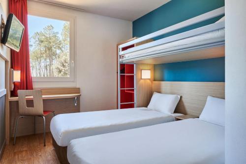 蒙德马桑Kyriad Direct Mont De Marsan - St Avit的客房设有两张床、一张桌子和一个窗户。
